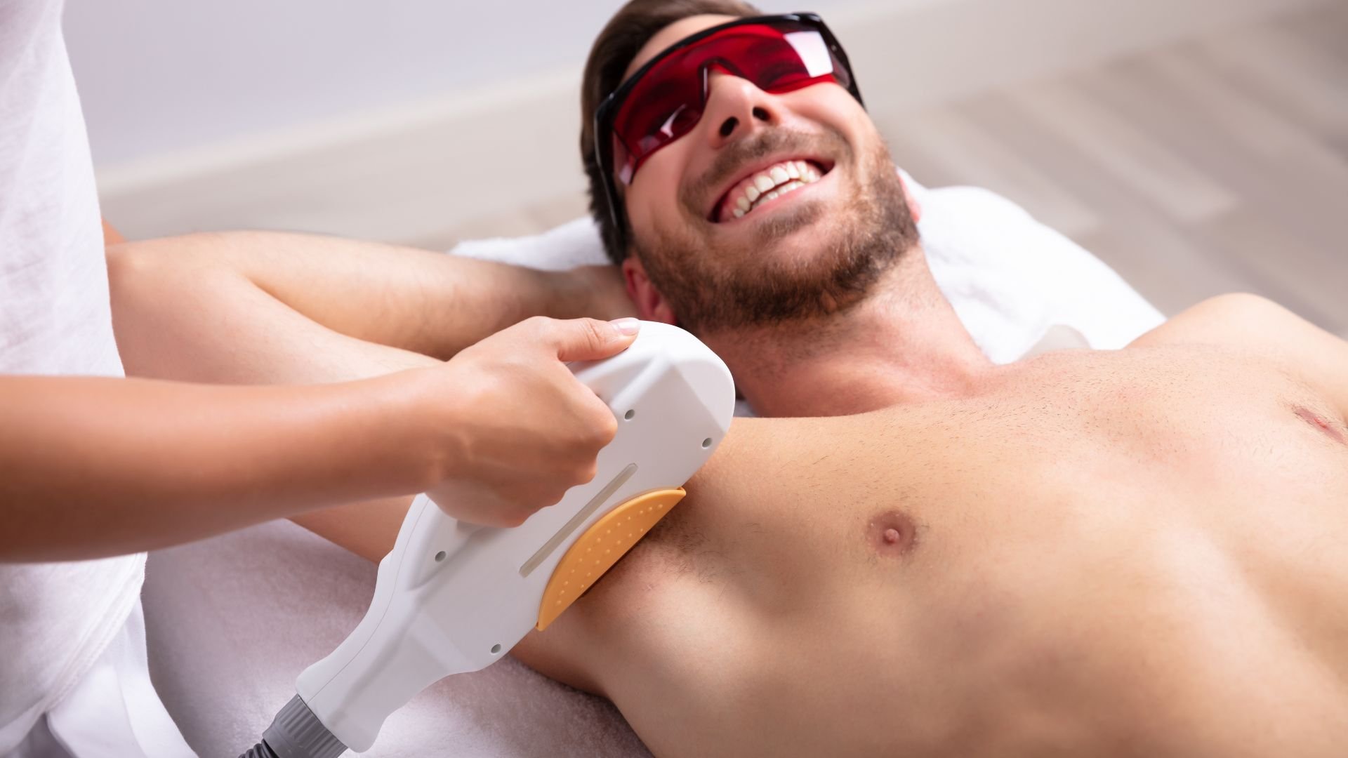 Man receiving laser hair removal treatment with protective glasses